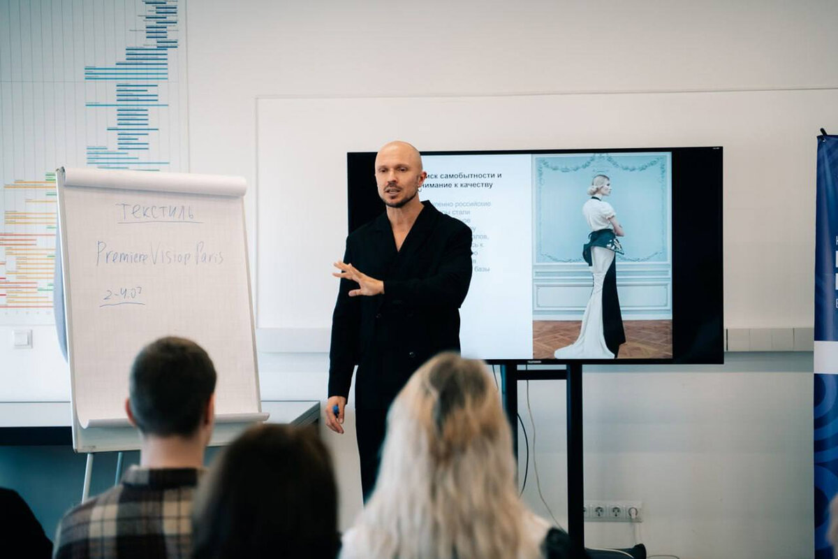 Anton Kopylov speaking beside a screen showing a couture gown, flipchart headed “Textile”