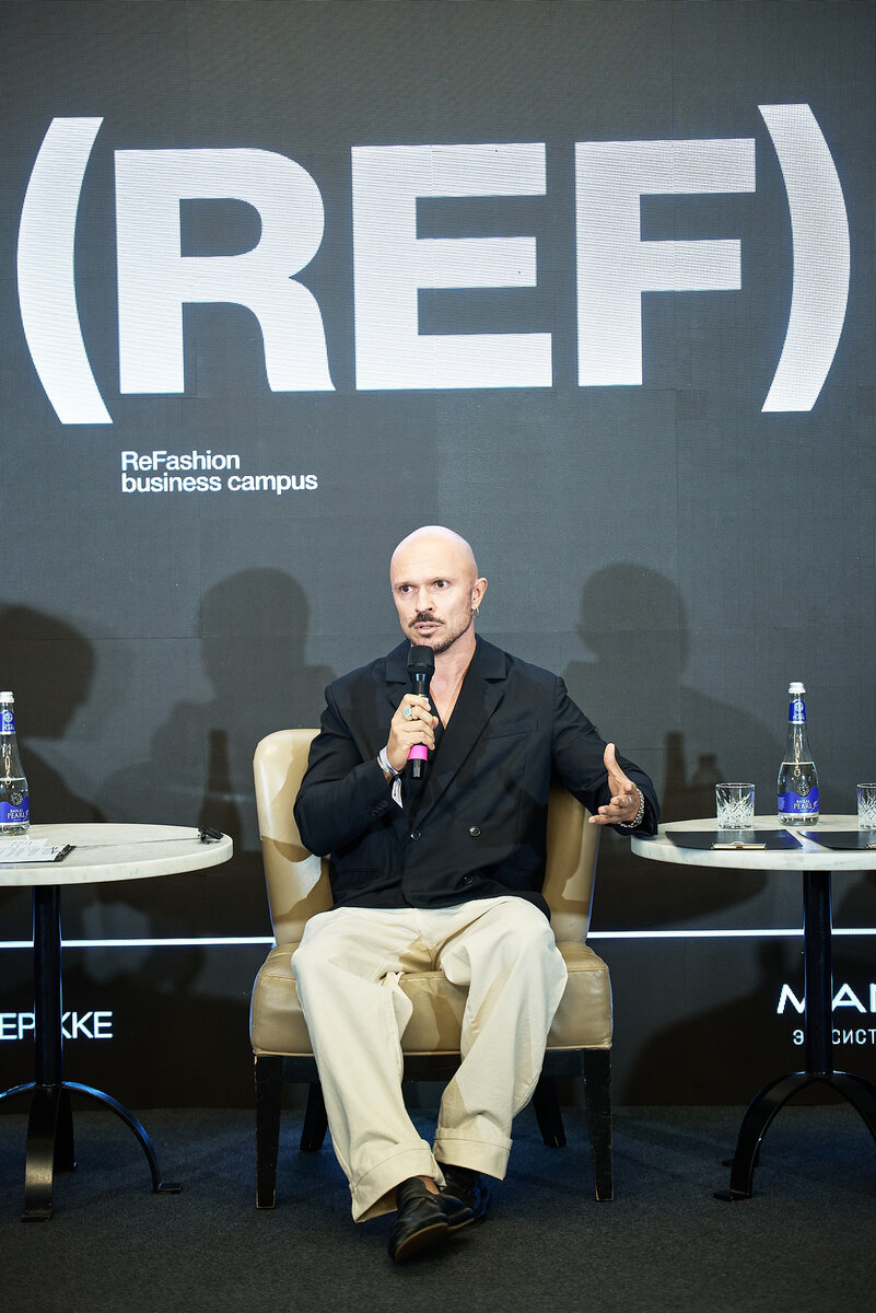 Anton Kopylov speaking on a panel in front of a ReFashion business campus backdrop