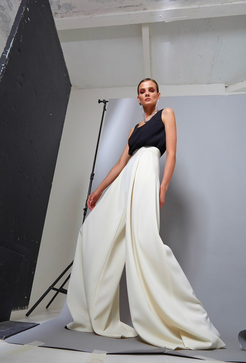 Model wearing black sleeveless top with ivory wide-leg trousers on a studio photoshoot