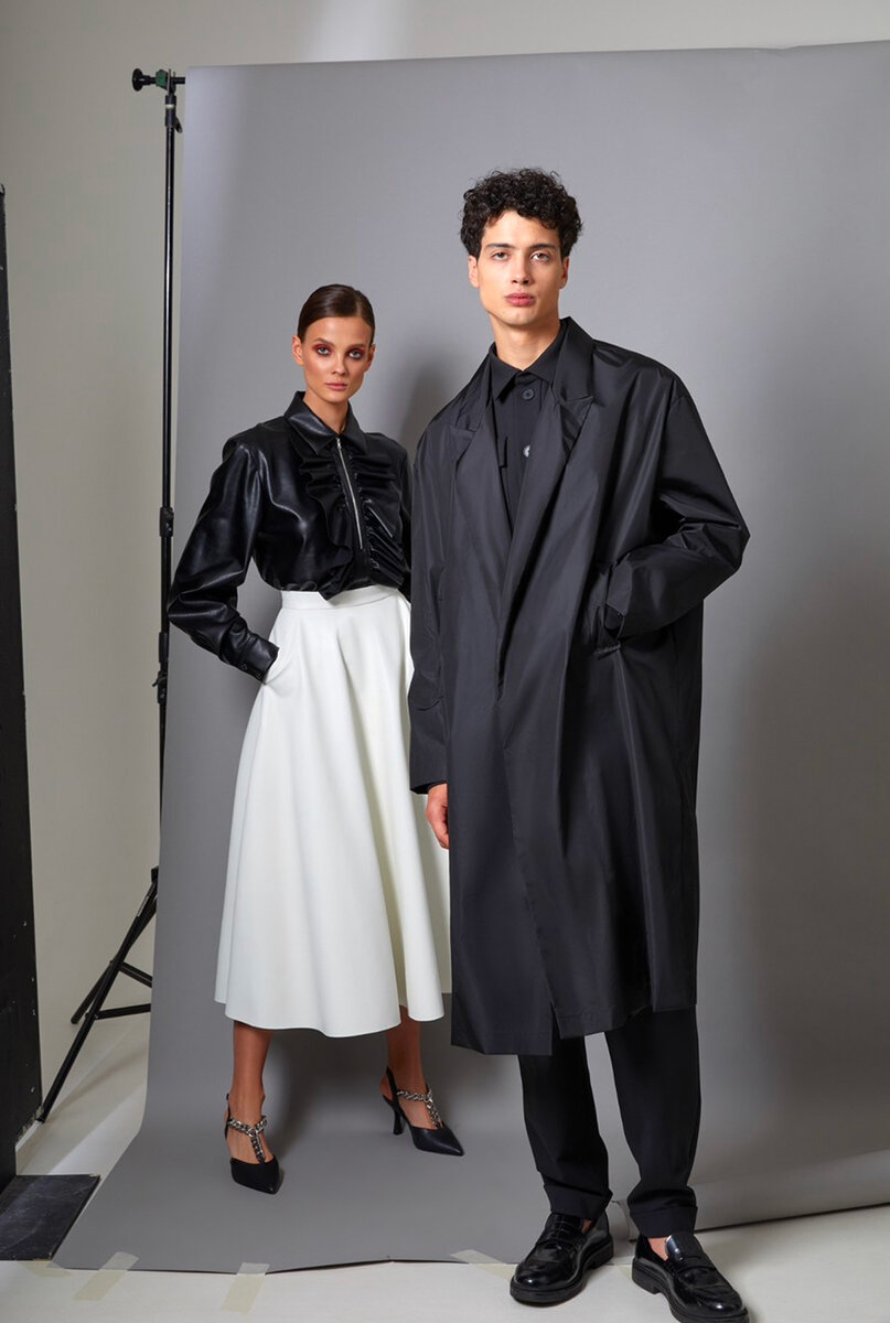 Two models: black leather ruffled shirt with white midi skirt, and an oversized black trench