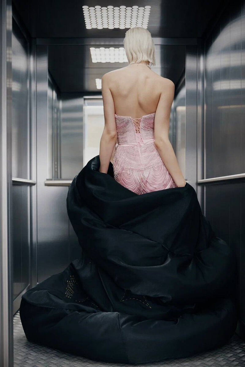 Back view of a pink crystal-mesh dress in a steel elevator