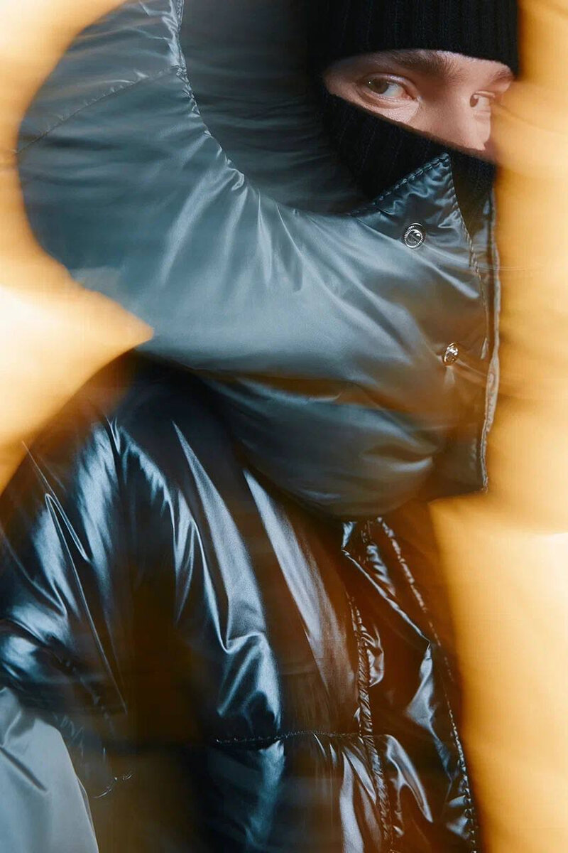 Motion-blurred shot of a glossy black puffer coat and knit balaclava